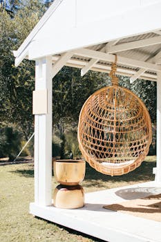 Stylish wicker swing in a sunny outdoor patio setting, perfect for relaxation.